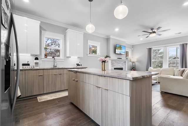 kitchen with stainless steel refrigerator with ice dispenser, crown molding, a kitchen island, pendant lighting, and white cabinets