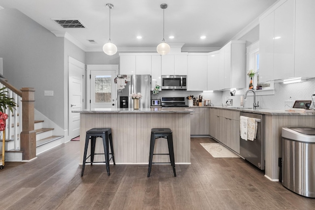 kitchen featuring appliances with stainless steel finishes, pendant lighting, sink, white cabinets, and a center island