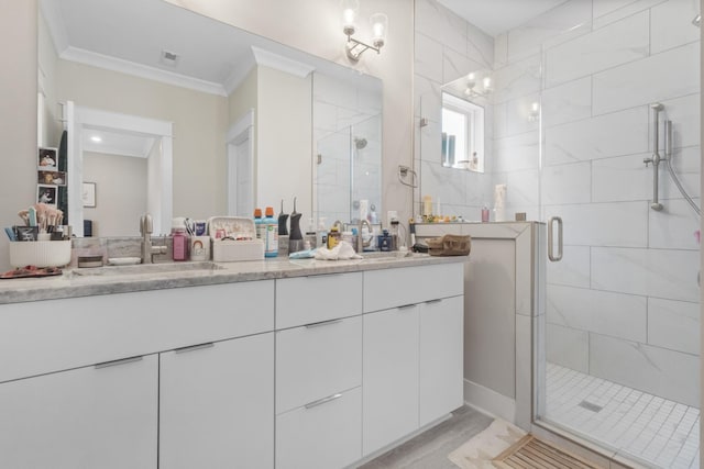 bathroom with vanity, a shower with shower door, and ornamental molding