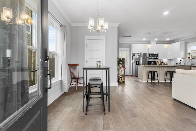 dining area with an inviting chandelier, ornamental molding, and plenty of natural light