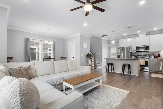 living room featuring ceiling fan with notable chandelier, wood-type flooring, and ornamental molding