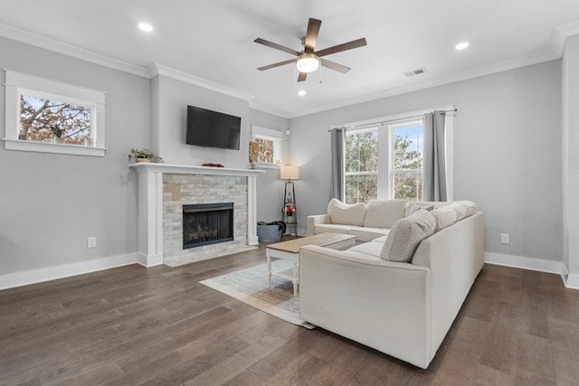 living room featuring a fireplace, crown molding, dark wood-type flooring, and ceiling fan