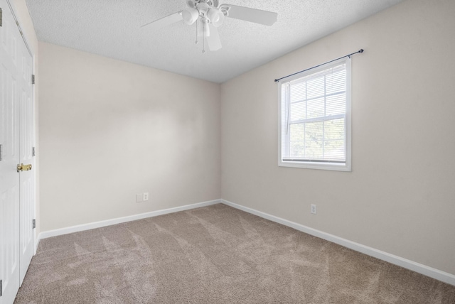 spare room featuring light carpet, ceiling fan, and a textured ceiling