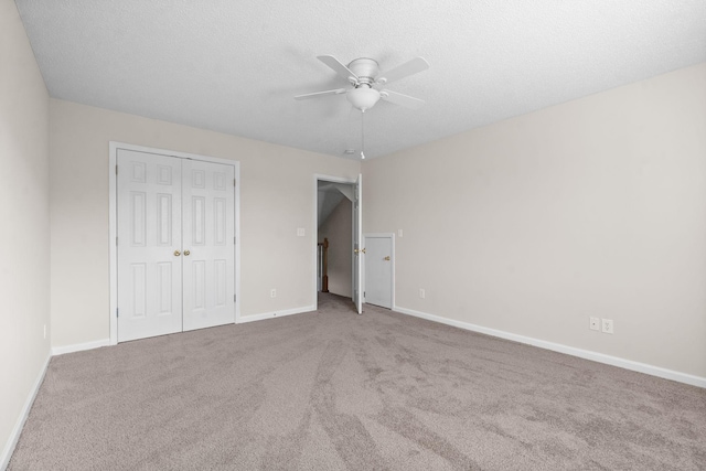 unfurnished bedroom featuring light carpet, ceiling fan, a closet, and a textured ceiling