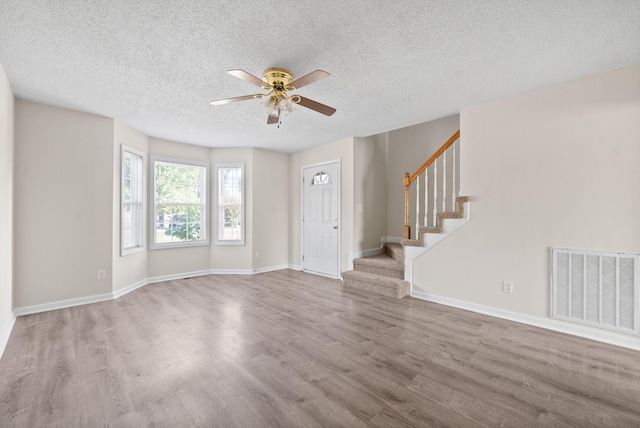 unfurnished living room with a textured ceiling, light hardwood / wood-style floors, and ceiling fan