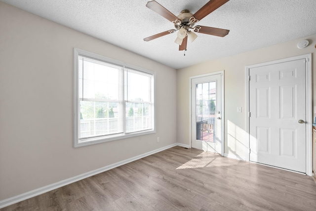 empty room featuring ceiling fan, light hardwood / wood-style flooring, and a textured ceiling