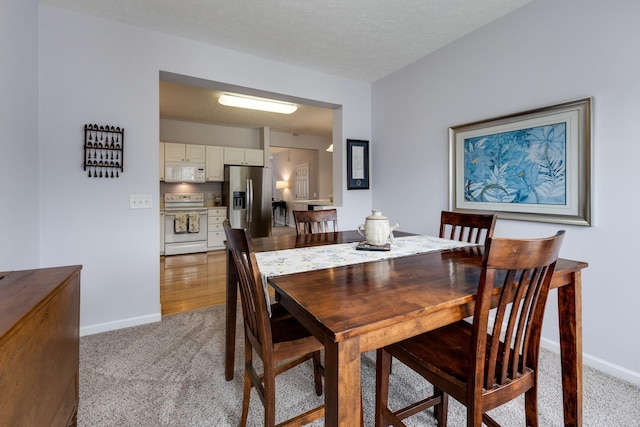 carpeted dining room with a textured ceiling