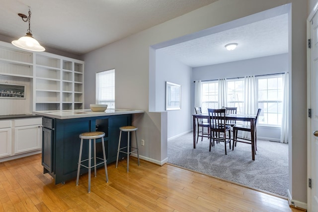 kitchen featuring a healthy amount of sunlight, decorative light fixtures, a breakfast bar, and white cabinets