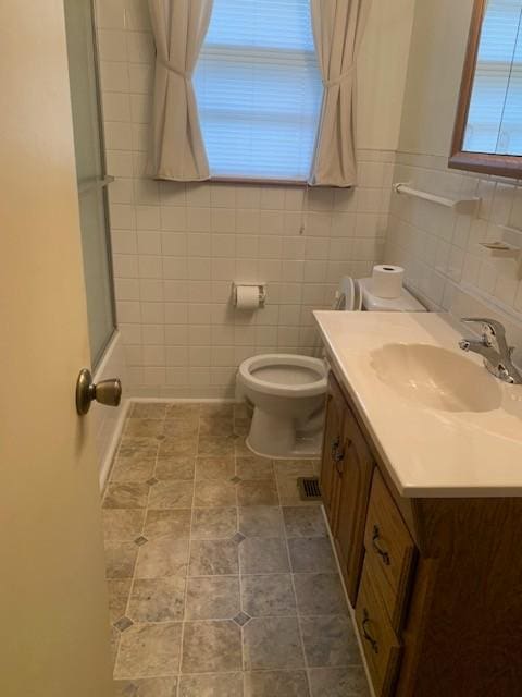 bathroom with vanity, tile walls, and toilet