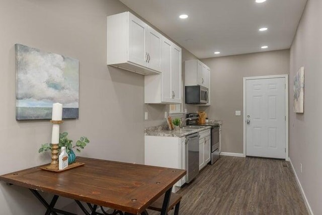 kitchen with white cabinets, stainless steel appliances, dark wood-type flooring, and light stone counters