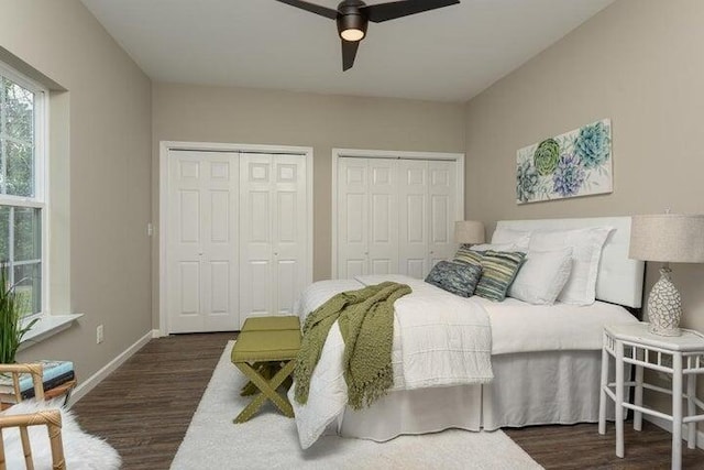 bedroom with dark hardwood / wood-style floors, two closets, and ceiling fan