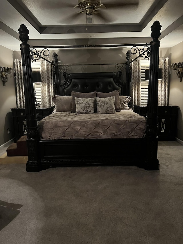 bedroom featuring ceiling fan, carpet flooring, and a tray ceiling