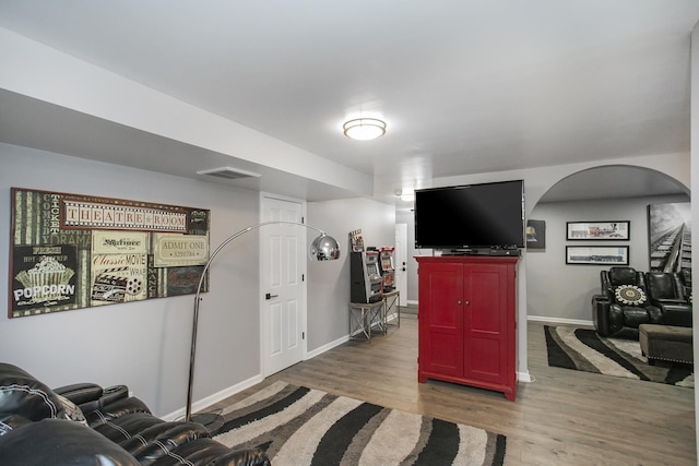 interior space featuring arched walkways, baseboards, wood finished floors, and visible vents