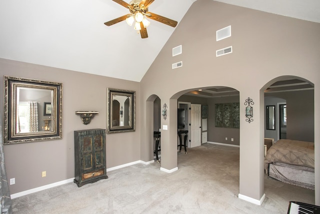 unfurnished living room with visible vents, a ceiling fan, light colored carpet, baseboards, and high vaulted ceiling