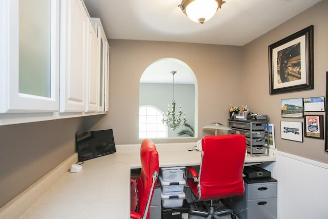 home office with arched walkways, wainscoting, and an inviting chandelier