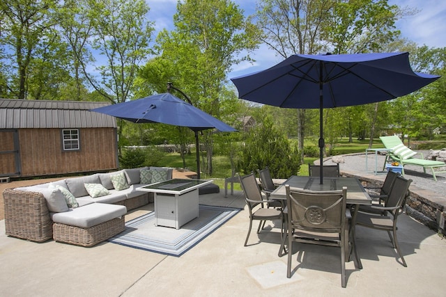 view of patio / terrace with an outdoor living space with a fire pit, a shed, outdoor dining space, and an outbuilding