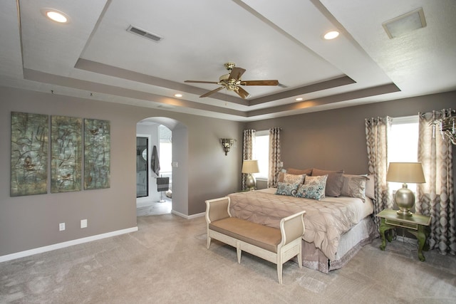 bedroom featuring a tray ceiling, arched walkways, visible vents, and recessed lighting