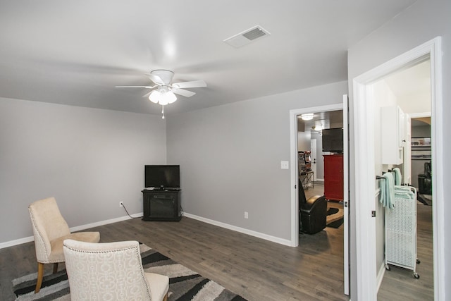 home office with dark wood-style floors, visible vents, a ceiling fan, and baseboards
