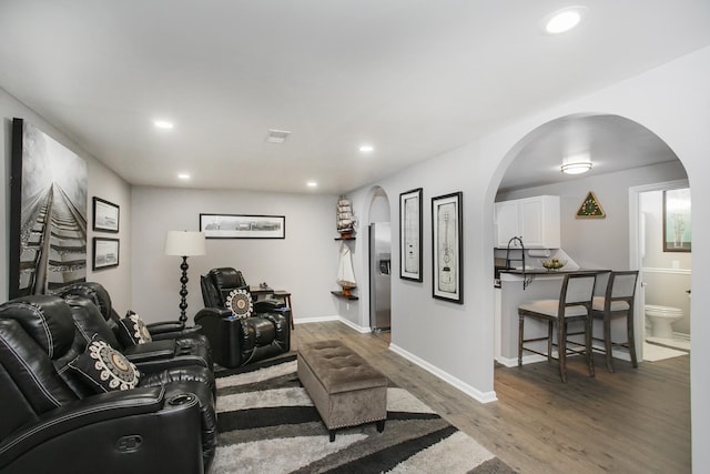 interior space featuring wood finished floors, recessed lighting, baseboards, and arched walkways