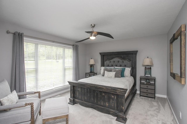 bedroom featuring light carpet, a ceiling fan, and baseboards
