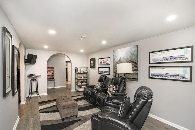 living area with baseboards, arched walkways, wood finished floors, and recessed lighting