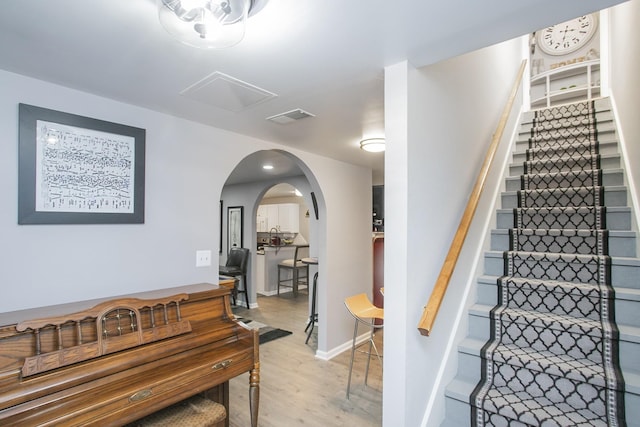 stairway featuring baseboards, visible vents, wood finished floors, and arched walkways