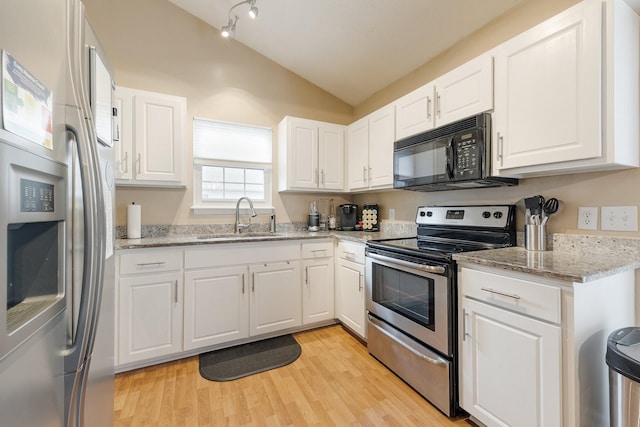 kitchen featuring lofted ceiling, sink, appliances with stainless steel finishes, white cabinetry, and light stone counters