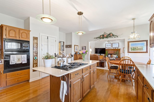 kitchen featuring black appliances, a center island, light hardwood / wood-style floors, and decorative light fixtures