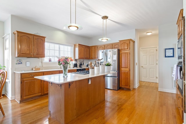 kitchen with light hardwood / wood-style flooring, a kitchen breakfast bar, decorative light fixtures, stainless steel refrigerator, and a center island