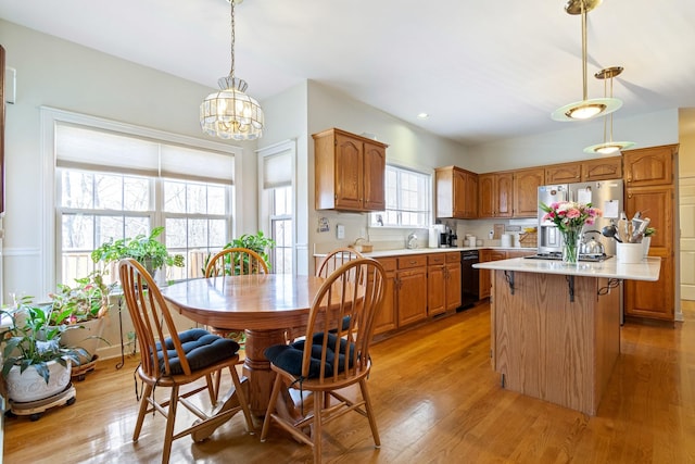 kitchen featuring black dishwasher, a center island, pendant lighting, light hardwood / wood-style floors, and stainless steel fridge