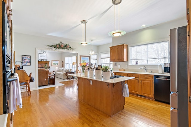 kitchen with a kitchen island, black dishwasher, stainless steel refrigerator, sink, and a kitchen bar