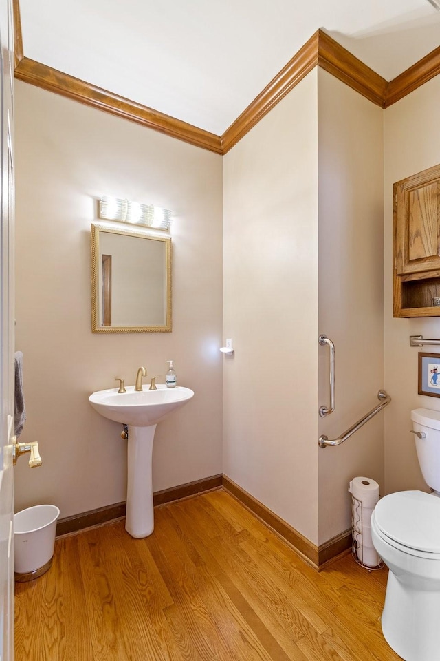 bathroom with crown molding, wood-type flooring, and toilet