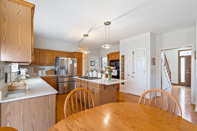 kitchen featuring plenty of natural light, hanging light fixtures, stainless steel appliances, a kitchen island, and sink