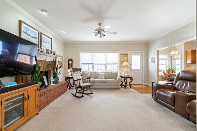 living room featuring light carpet, crown molding, ceiling fan with notable chandelier, and a fireplace