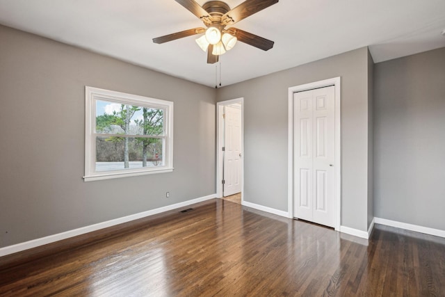 unfurnished bedroom with dark wood-type flooring, a closet, and ceiling fan