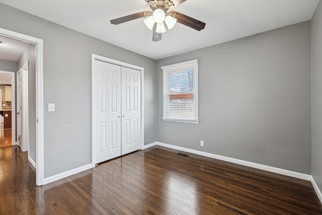 unfurnished bedroom featuring dark wood-type flooring, ceiling fan, and a closet