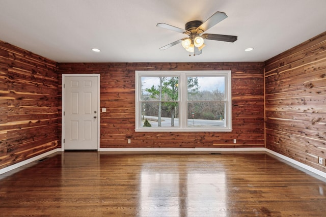 spare room with wooden walls, ceiling fan, and dark hardwood / wood-style floors