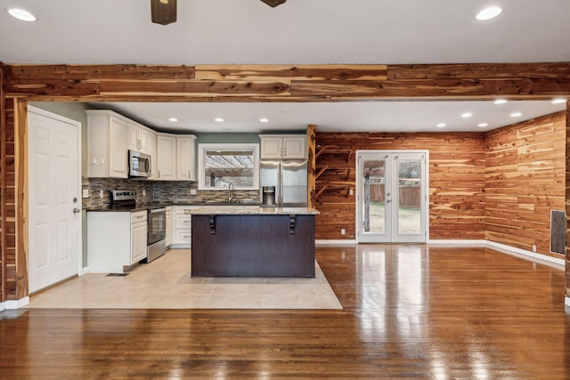 kitchen with sink, beam ceiling, stainless steel appliances, white cabinets, and a kitchen island