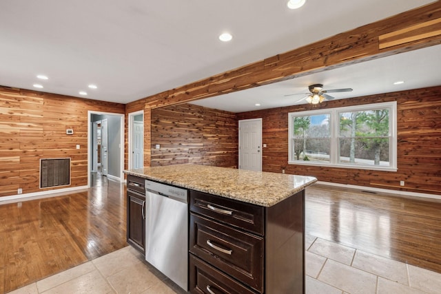 kitchen featuring light stone counters, stainless steel dishwasher, dark brown cabinetry, and beamed ceiling