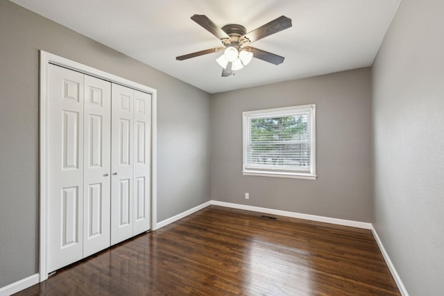 unfurnished bedroom featuring ceiling fan, dark hardwood / wood-style floors, and a closet