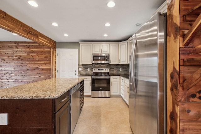 kitchen with stainless steel appliances, white cabinetry, backsplash, and light stone counters