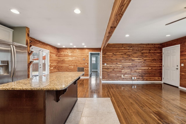 kitchen featuring beam ceiling, a kitchen breakfast bar, dark hardwood / wood-style floors, light stone counters, and a kitchen island