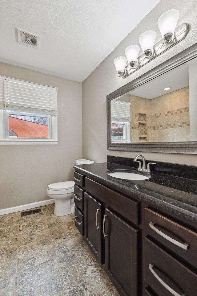 bathroom with vanity, toilet, and a textured ceiling