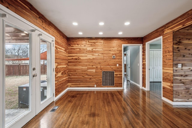 empty room with plenty of natural light, dark hardwood / wood-style floors, and wood walls