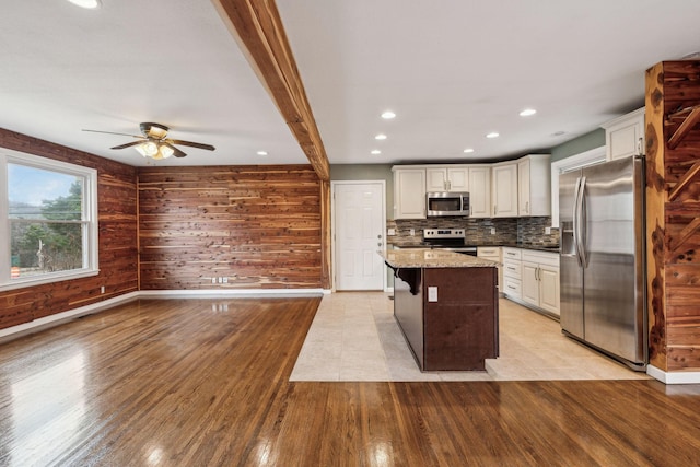 kitchen featuring a breakfast bar area, dark stone countertops, backsplash, a center island, and stainless steel appliances