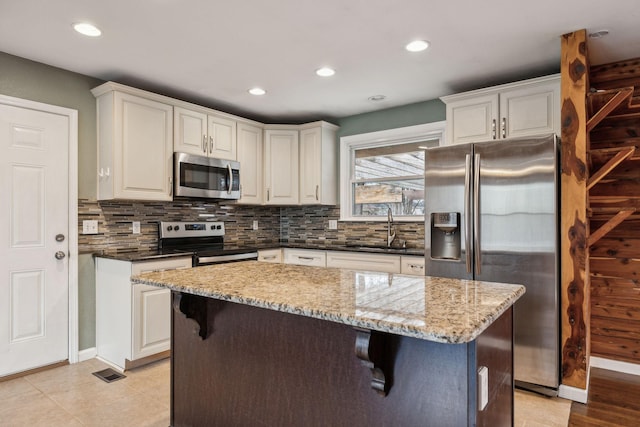 kitchen featuring sink, white cabinetry, dark stone counters, stainless steel appliances, and backsplash