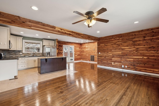 kitchen with a breakfast bar area, a center island, light wood-type flooring, beamed ceiling, and stainless steel appliances