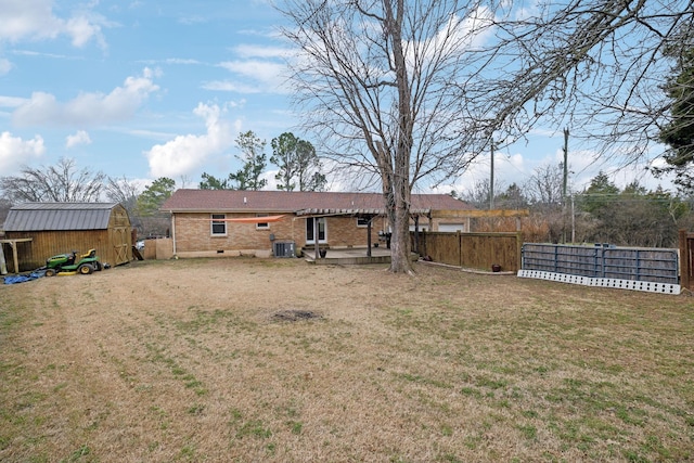 back of house featuring a shed, a yard, and central air condition unit