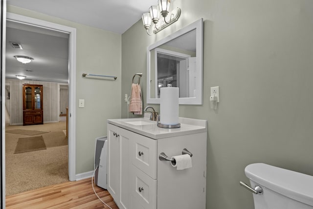 bathroom featuring vanity, a notable chandelier, wood-type flooring, and toilet