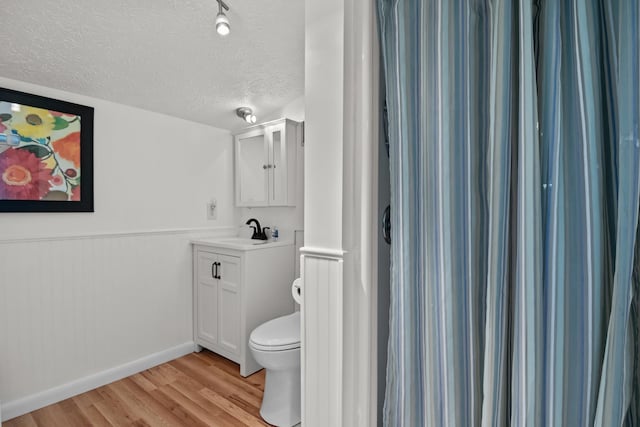 bathroom with vanity, toilet, wood-type flooring, and a textured ceiling